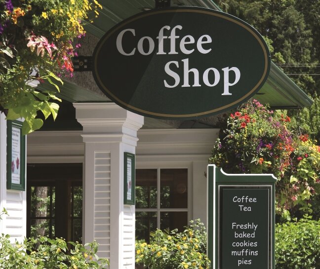 A vibrant green coffee shop sign featuring vinyl lettering, showcasing the name or logo of the café with eye-catching appeal.